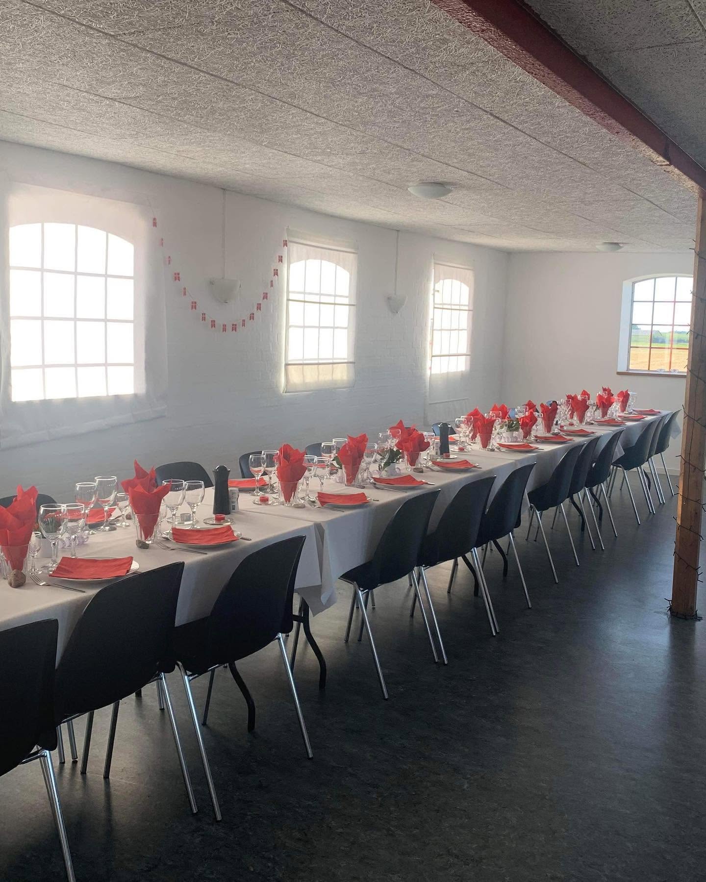 Langbord i festlokalet pyntet til fest med hvid dug, røde servietter og dansk flagguirlande