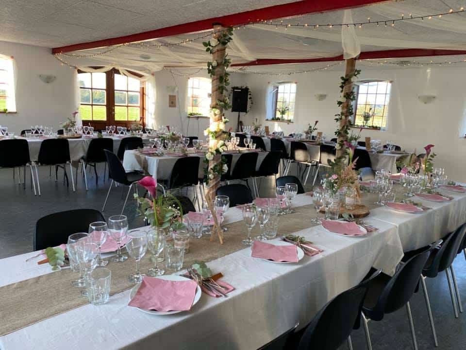 Hele festlokalet pyntet til fest med dækkede langborde, lyskæder og blomster